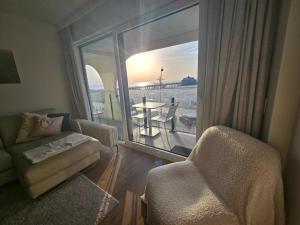 a living room with a balcony with a chair and a window at Isola Bella - Luxe Verblijf op de Zeedijk met Panoramisch Uitzicht in Blankenberge