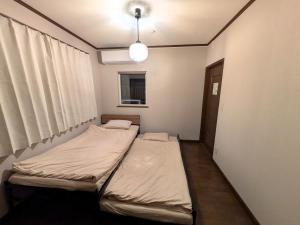 two beds in a small room with a window at Frasis in Furano