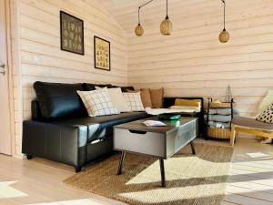 a living room with a black leather couch and a table at 204 Hochwertiges Tiny House mit Wiesenblick in Bleckede