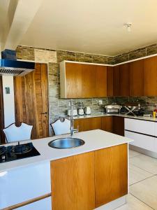a kitchen with a sink and wooden cabinets at Mosia Guest House in Maseru