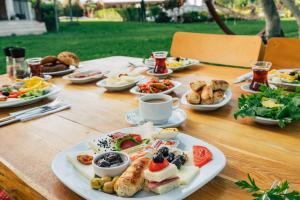 a wooden table with plates of food on it at Helen Troya Hotel Geyikli in Çanakkale
