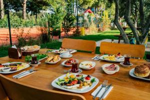 a wooden table with plates of food on it at Helen Troya Hotel Geyikli in Çanakkale