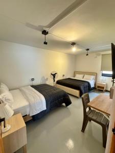 a hotel room with two beds and a table and a desk at Hostal Casa Iwa in Medellín +81 photos