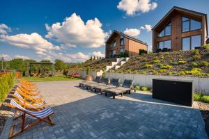a patio with lounge chairs and a house on a hill at Zajęcze Domki in Zagórze Śląskie