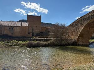 an old bridge over a river in front of a building at Masía El Losar - Casa Rural Exclusiva Castellón in Villafranca del Cid