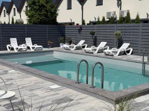 a swimming pool with white lounge chairs and a row at BalticMoon Rewal Domki z Podgrzewanym Basenem in Rewal