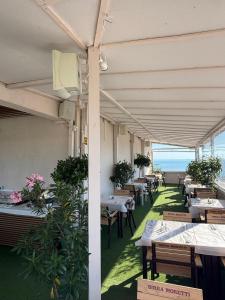 a restaurant with tables and chairs with the ocean in the background at Hotel Promenada in Mamaia