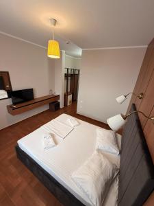 a large bed in a room with a lamp at Hotel Promenada in Mamaia
