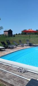 a swimming pool with chairs and an umbrella at Chambre d'hôtes Bidegaina in Ahetze