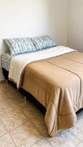 a bed with a blanket on it in a room at Casa do Lago in Londrina