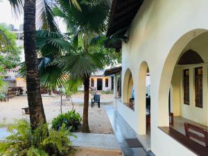 a building with palm trees next to a courtyard at Hakkeem's Homestay in Arugam Bay
