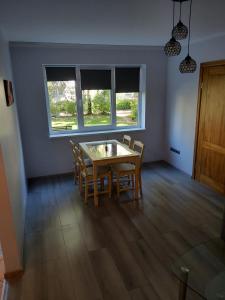 a dining room with a table and chairs and two windows at Apartament orhideja 11 in Riga