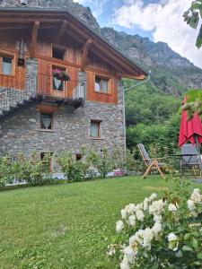 a house with a balcony and a table and a chair at Le Camere di Naturalys - ospitalità in azienda agricola in Gaby