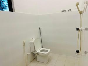 a bathroom with a toilet in a white room at Hakkeem's Homestay in Arugam Bay