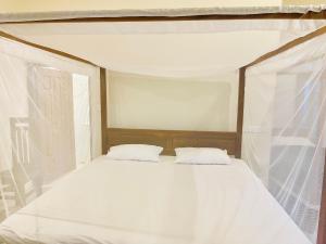 a white bed with two pillows in a room at Hakkeem's Homestay in Arugam Bay