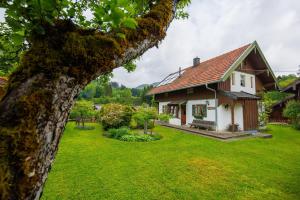 a white house with a green yard and a tree at Ferienhaus Hallweger inkl. Chiemgaukarte in Ruhpolding