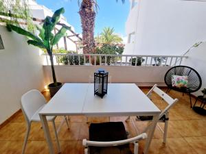 a white table and chairs on a balcony with palm trees at Teguisol Breeze en Costa Teguise in Costa Teguise