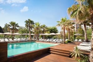 a swimming pool with chairs and umbrellas at a resort at Renaissance Aix-en-Provence Hotel in Aix-en-Provence