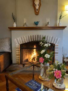 a living room with a fireplace with flowers on a table at Hotel El Ciervo in Villarrica +54 photos