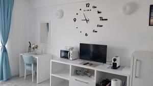 a white room with a tv and a clock on the wall at Studio Lucian in Douăzeci şi Trei August +29 photos