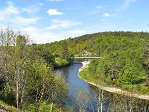 a river with a bridge in the distance at Sycamore Cottage - Uk45923 in Ballater