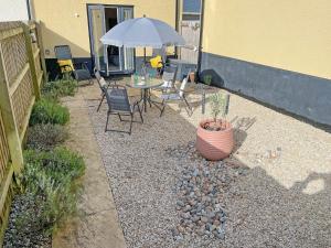 a patio with a table and chairs and an umbrella at Wagtails in Dartmouth