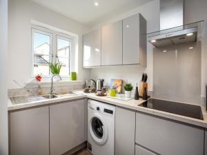 a white kitchen with a washing machine in it at Wagtails in Dartmouth
