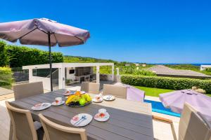 a table with a bowl of fruit and an umbrella at Villa Vatia 2 in Tragaki