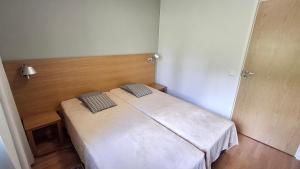 a small bedroom with a white bed with two pillows at Saimaan Rantavilla Zebra in Imatra