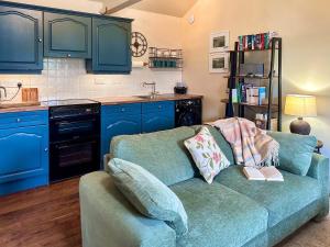 a blue couch in a kitchen with blue cabinets at The Owlery At Aysgarth in Aysgarth