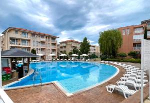 a large swimming pool with white chairs and umbrellas at Апартамент ШАХОВ in Tŭnkovo