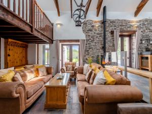 a living room with couches and a stone wall at Wheelwright Barn in Llangain