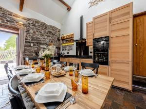 a dining room with a wooden table and a kitchen at Wheelwright Barn in Llangain +18 photos