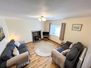 a living room with two couches and a fireplace at Willesdene Cottage in Abernethy