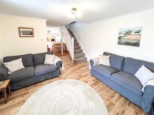 a living room with a blue couch and a staircase at Willesdene Cottage in Abernethy