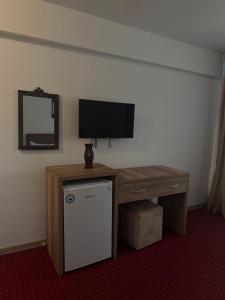 a room with a desk with a television and a table with a refrigerator at Hotel Ibiza in Eforie Nord