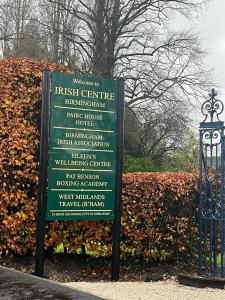 a sign in front of a bush next to a fence at Pairc House Hotel in Birmingham
