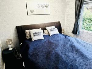 a bedroom with a blue bed with pillows on it at Chalet op de veluwe in Putten