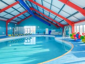 a large indoor swimming pool with blue walls and red beams at Sunshine & Smiles in South Hayling