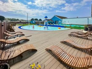 a playground with lounge chairs and a swimming pool at Sunshine & Smiles in South Hayling