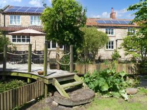 a garden with a wooden bridge in front of a house at Rose Croft in Pickering