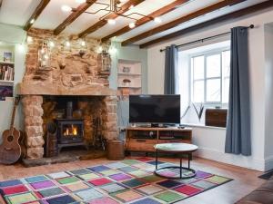 a living room with a stone fireplace and a television at Rose Croft in Pickering +8 photos