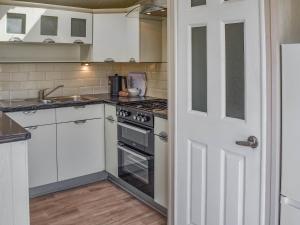 a kitchen with white cabinets and a stove top oven at Sandbank in Bacton