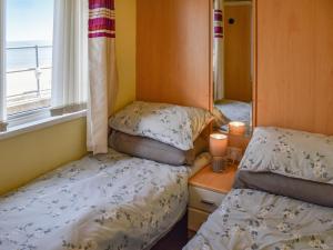 two beds in a small room with a window at Sandbank in Bacton