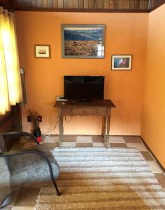 uma sala de estar com uma mesa e uma televisão na parede em Chalé Pura Vida em São Roque de Minas