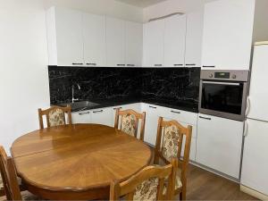 a kitchen with a wooden table and white cabinets at Paradise apartament in Prishtinë