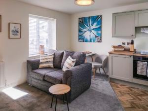 a living room with a couch and a kitchen at Dunlin in Filey