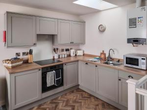 a kitchen with white cabinets and a wooden floor at Dunlin in Filey
