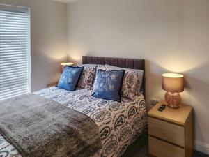 a bedroom with a bed with blue pillows at Dunlin in Filey +5 photos