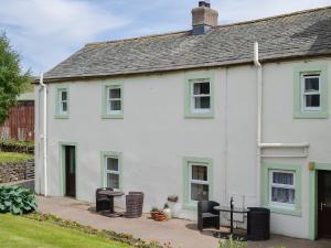 a white house with green windows and a patio at Swaledale Cottag in Caldbeck +12 photos